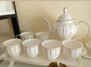 A set of tea mug  in color white set with a servicing kettle.