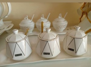 A set of sugar containers with spoons.